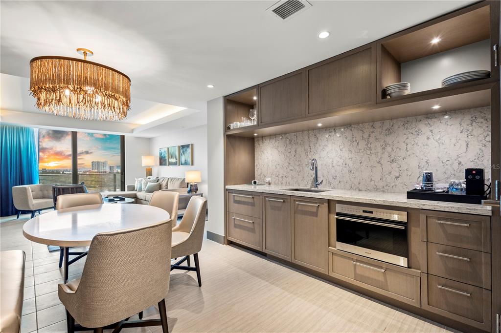 A kitchen area with wood cabinets, stone countertops, and an adjacent dining space — 691 S GULFVIEW BOULEVARD UNIT 1211, CLEARWATER BEACH, FL