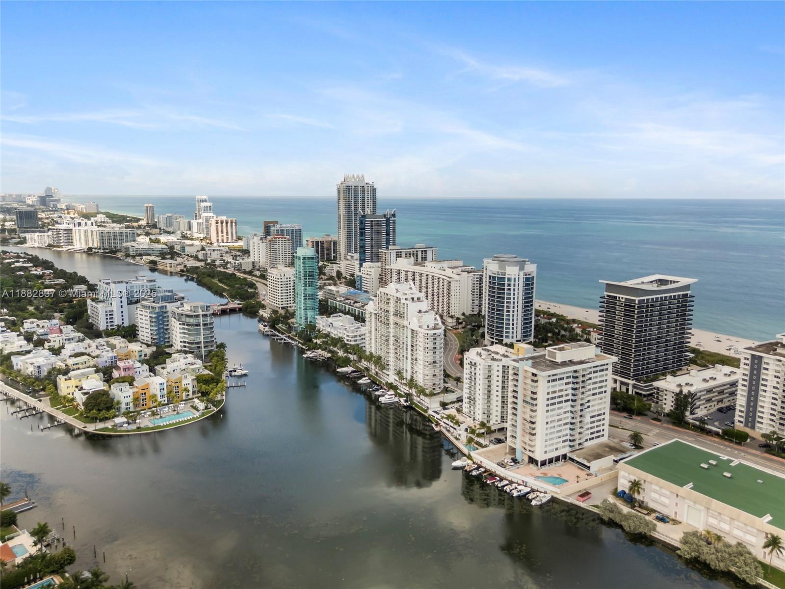 An aerial view shows a waterway lined with high-rise residential buildings and coastal scenery — 5900 Collins Ave # 604, Miami Beach FL 33140, MIAMI BEACH, FL