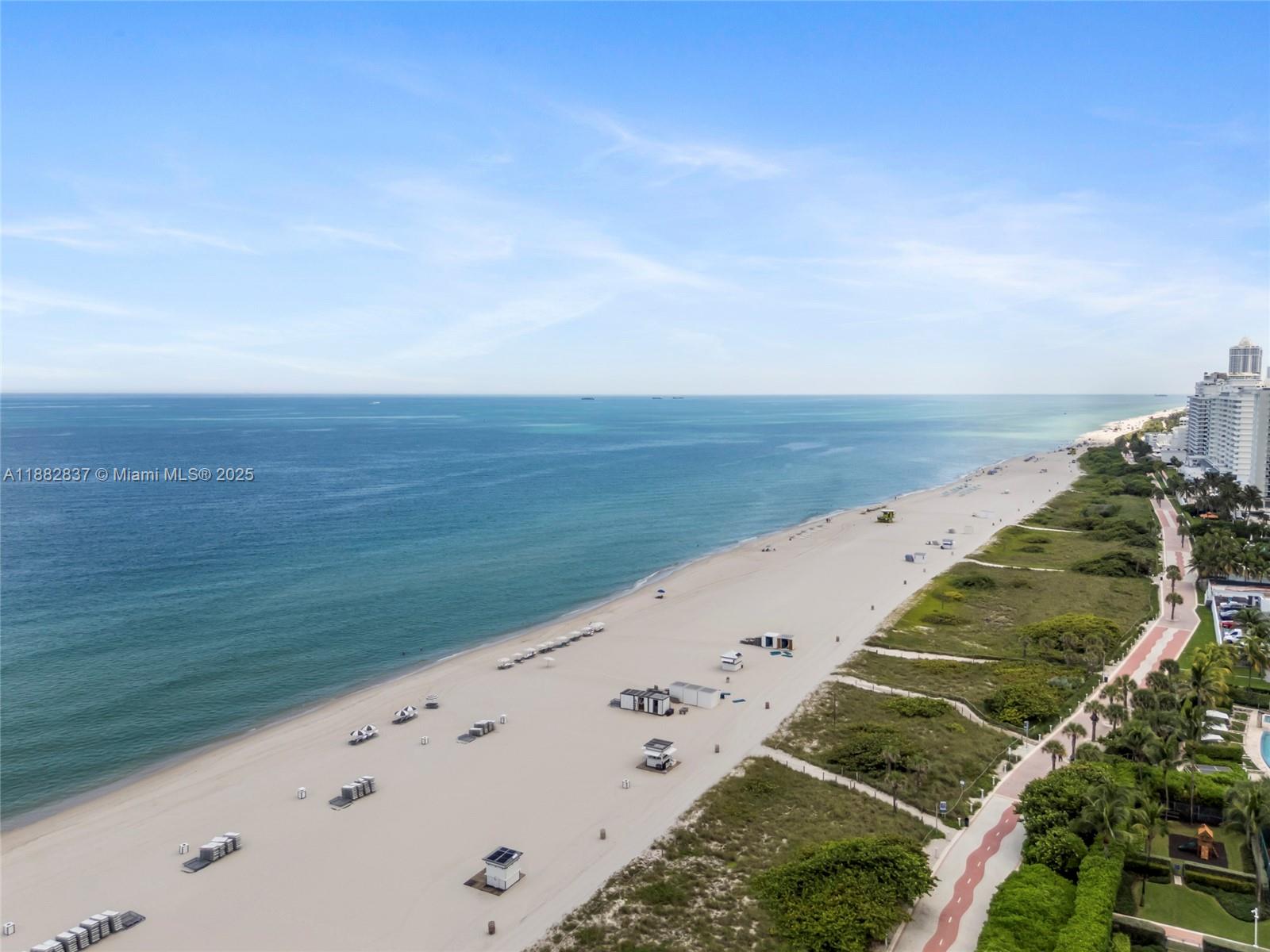 An aerial view shows a sandy beach, ocean, and a paved path along vegetation — 5900 Collins Ave # 604, Miami Beach FL 33140, MIAMI BEACH, FL