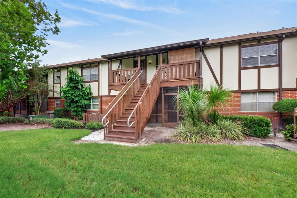 A two-story apartment building exterior features a wooden staircase leading to an upper-level balcony — 5301 HANSEL AVENUE UNIT A-18, EDGEWOOD, FL