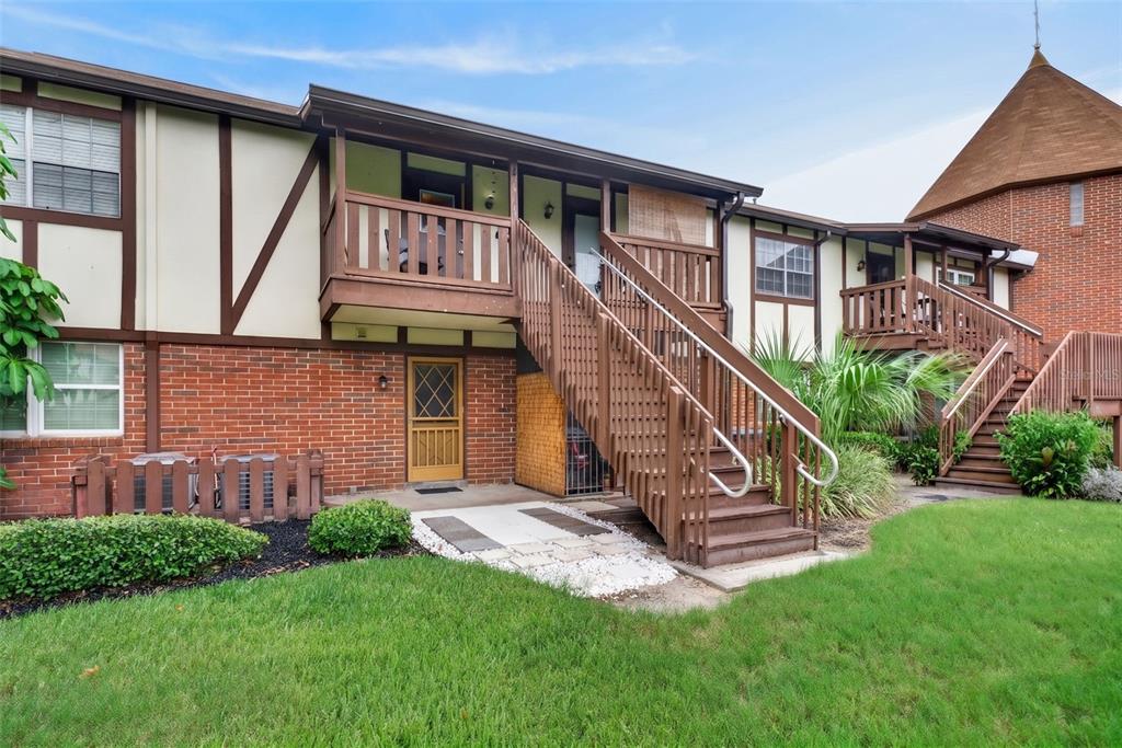 A two-story brick and stucco apartment building features wooden exterior staircases and balconies — 5301 HANSEL AVENUE UNIT A-18, EDGEWOOD, FL