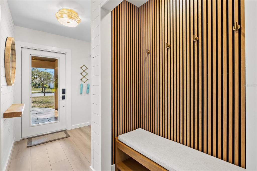 An entryway features a slatted wood accent wall with hooks, a bench, and a glass door — 2641 HYDE PARK STREET, SARASOTA, FL