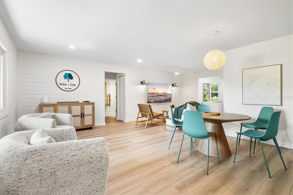 A bright living and dining area features white shiplap walls, light wood flooring, and furniture — 2641 HYDE PARK STREET, SARASOTA, FL