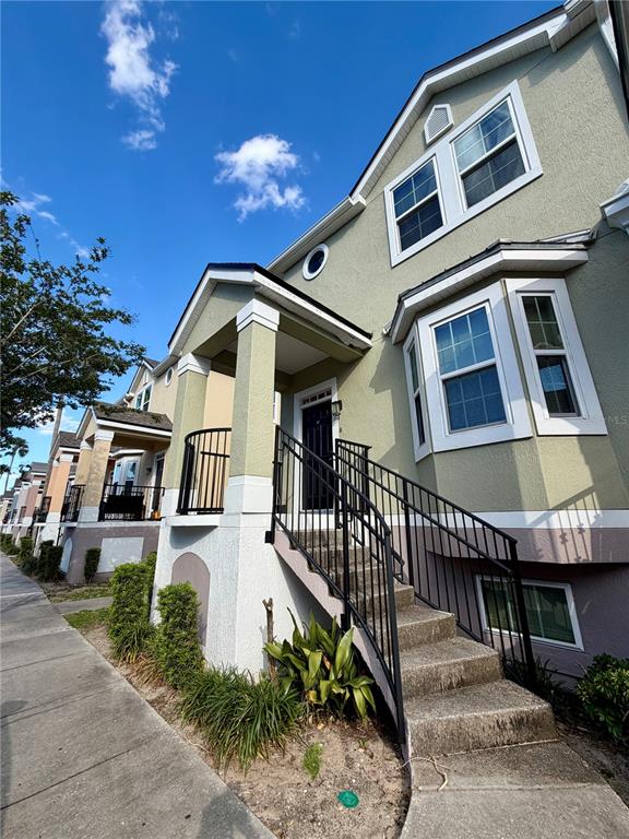 A multi-story townhouse exterior features a raised front entrance with black metal railings — 6648 TIME SQUARE AVENUE UNIT 105, ORLANDO, FL