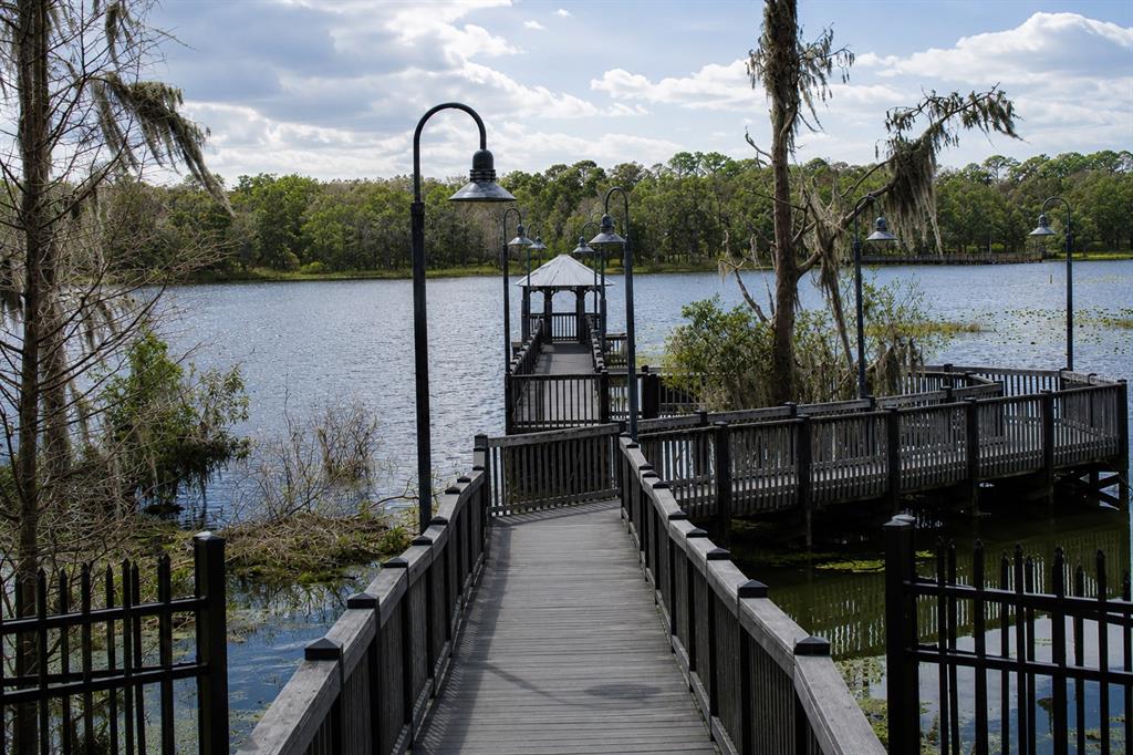 A wooden boardwalk leads to a gazebo over a lake surrounded by trees — 6648 TIME SQUARE AVENUE UNIT 105, ORLANDO, FL