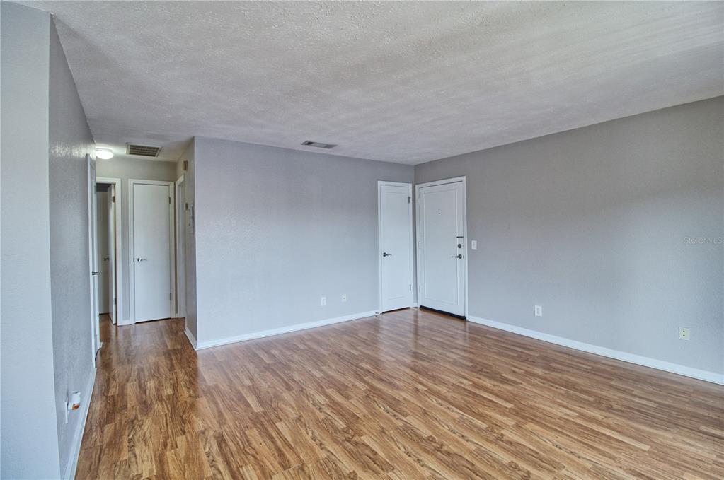 An empty room with gray walls, wood-look flooring, and several white doors — 13760 ORANGE SUNSET DRIVE UNIT 201, TAMPA, FL