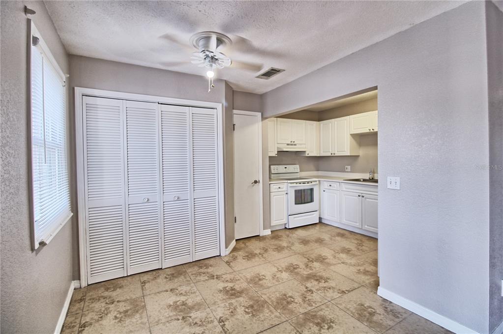 A kitchen and dining area feature white cabinets, tile flooring, and a ceiling fan — 13760 ORANGE SUNSET DRIVE UNIT 201, TAMPA, FL