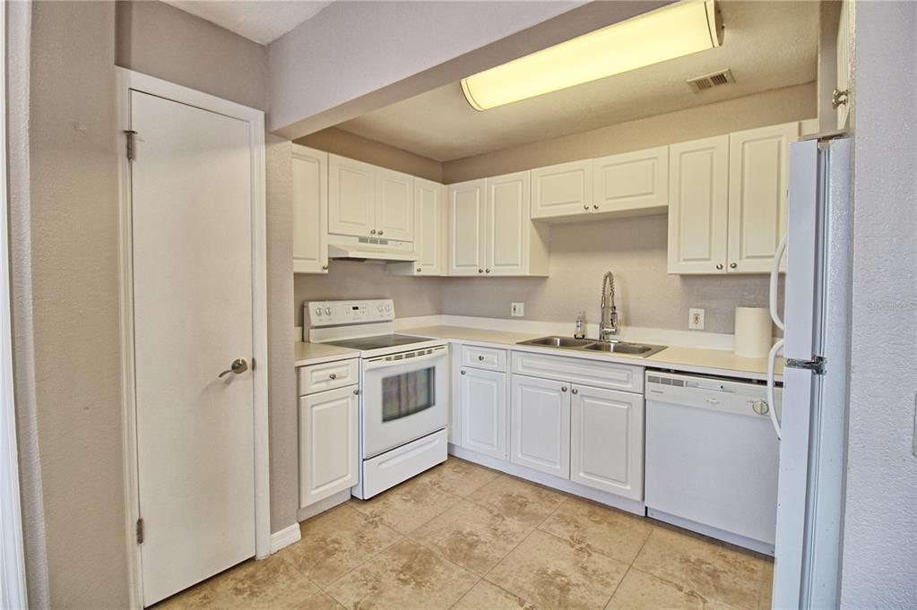 A kitchen with white cabinets, white appliances, a double sink, and light-colored tile flooring — 13760 ORANGE SUNSET DRIVE UNIT 201, TAMPA, FL
