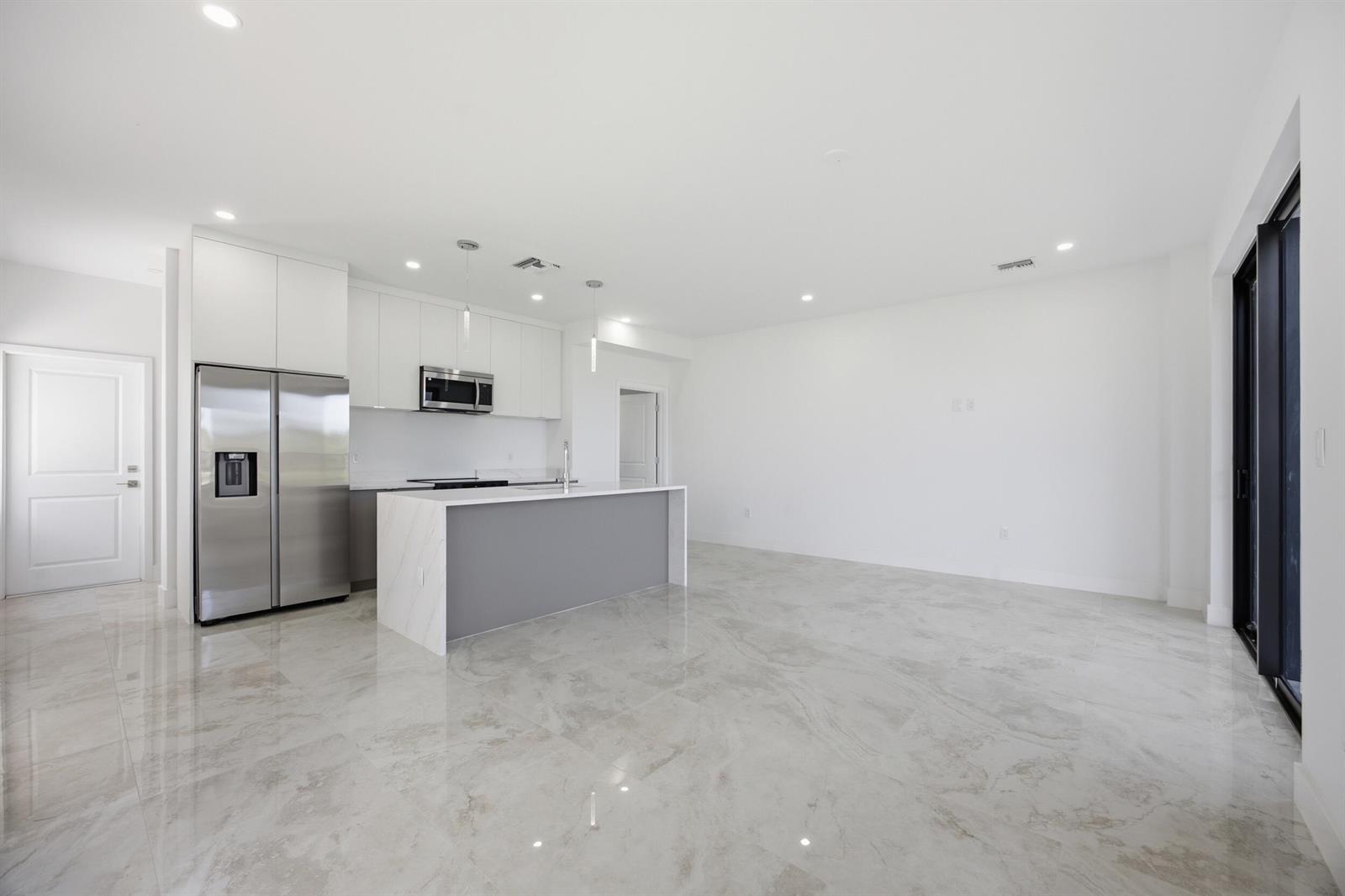 A modern kitchen with white cabinets, stainless steel appliances, and a gray island on tile — 1542 NW 1st Avenue, Pompano Beach FL 33060, POMPANO BEACH, FL