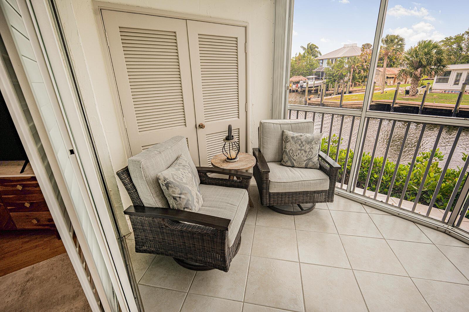 A screened-in balcony features two wicker chairs, a small side table, and a water view — 3901 SE Saint Lucie Boulevard # 13, Stuart FL 34997, STUART, FL