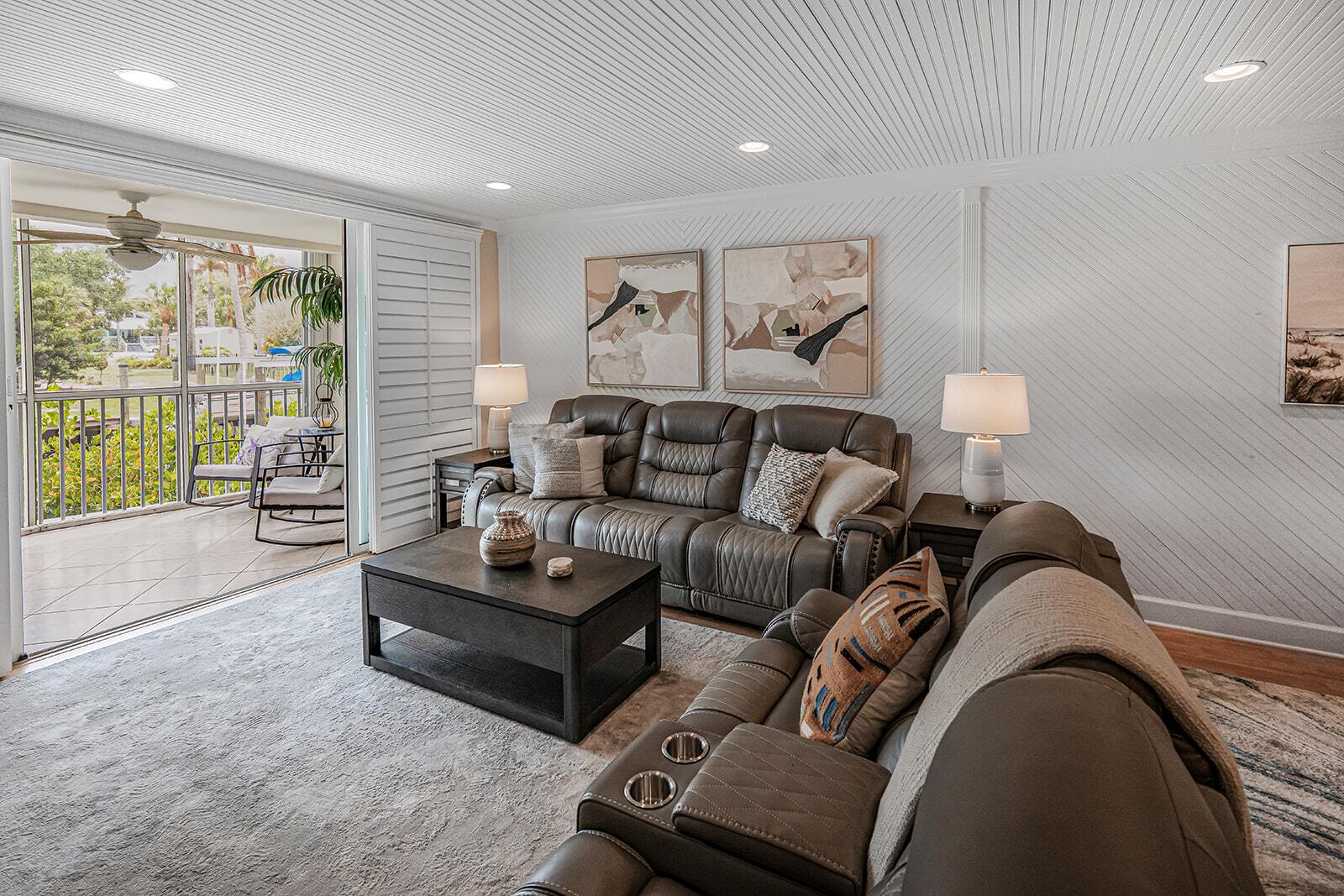 A living room with a grey sofa, television, and sliding doors opening to a waterfront balcony — 3901 SE Saint Lucie Boulevard # 13, Stuart FL 34997, STUART, FL