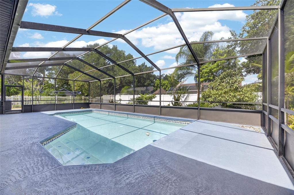 A screened-in swimming pool area with a concrete deck and a white privacy fence — 10409 HARVESTIME PLACE, RIVERVIEW, FL