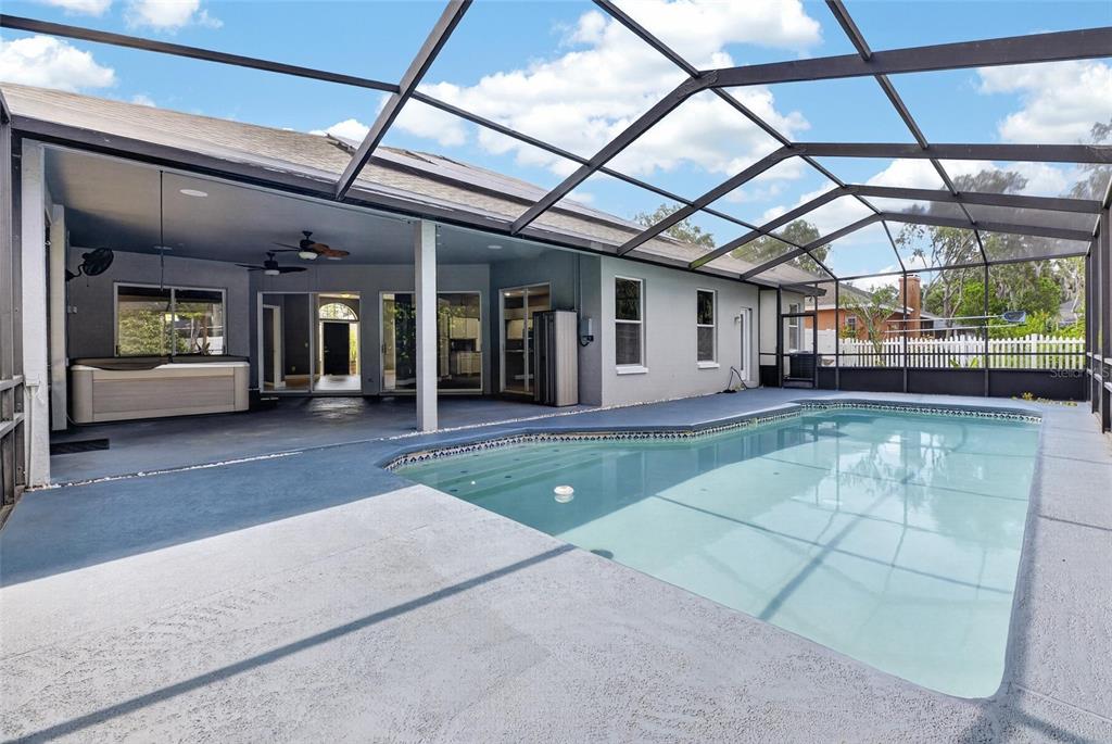 A screened-in patio features a swimming pool, a hot tub, and a covered seating area — 10409 HARVESTIME PLACE, RIVERVIEW, FL