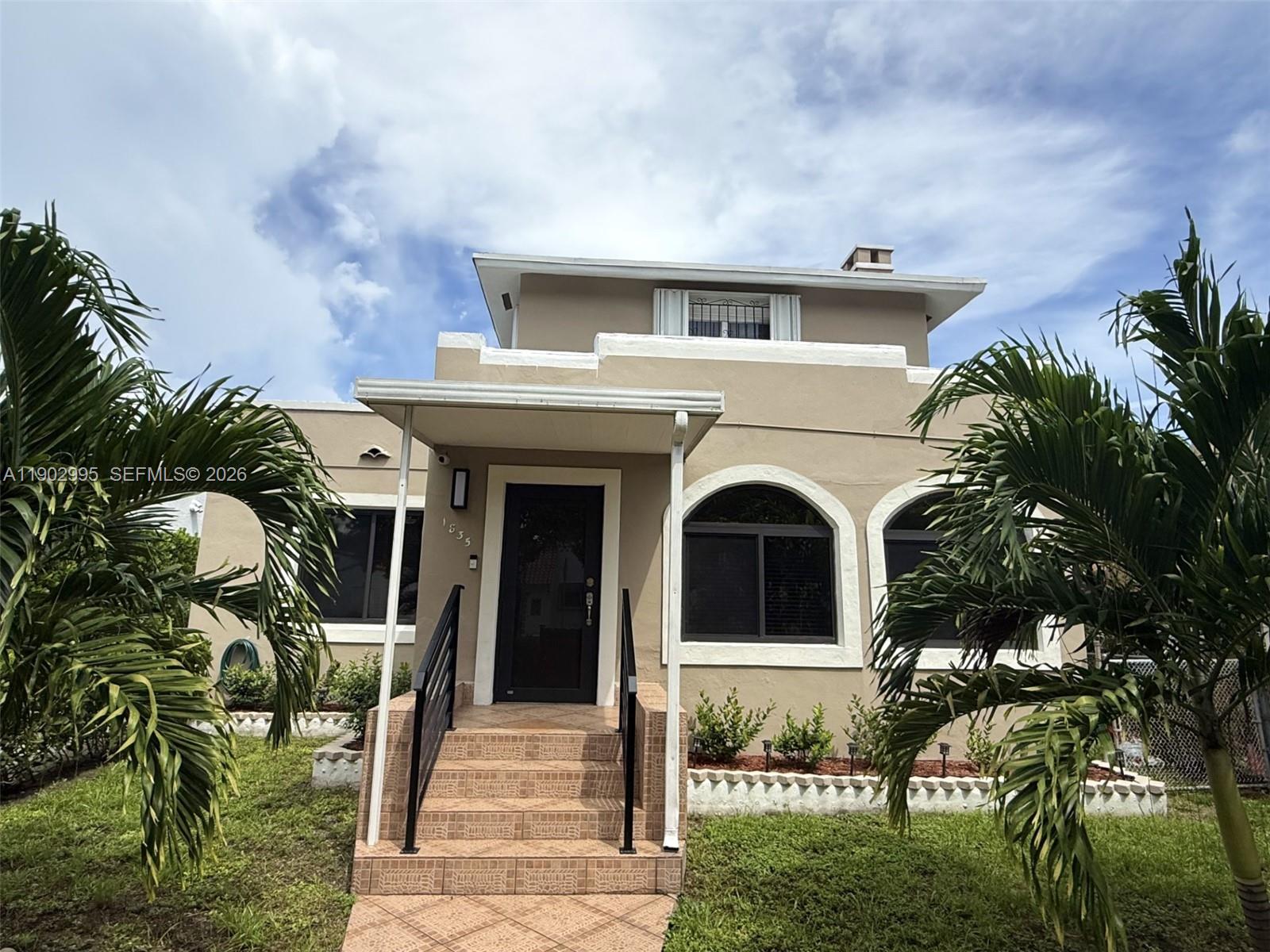 A tan two-story house features arched windows, a tiled front staircase, and palm trees — 1835 SW 10th St, Miami FL 33135, MIAMI, FL