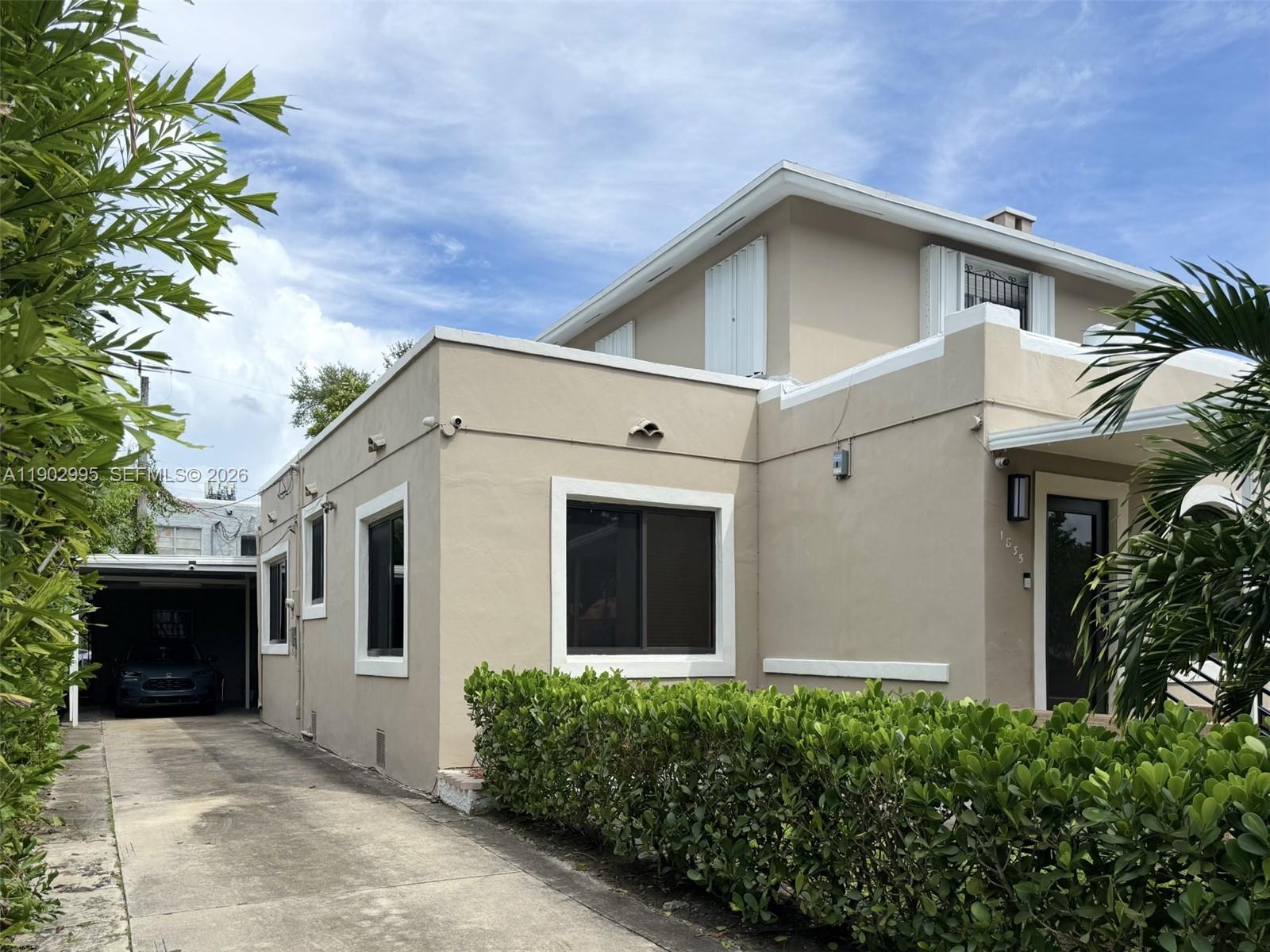 A beige two-story house features a concrete driveway, a carport, and a manicured hedge — 1835 SW 10th St, Miami FL 33135, MIAMI, FL