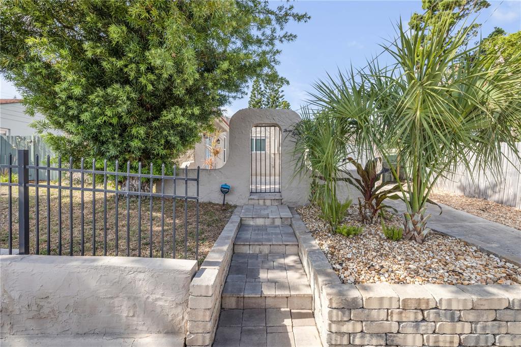 A paved walkway with steps leads to a gated arched entrance in a stucco wall — 315 SEARS AVENUE, DAYTONA BEACH, FL