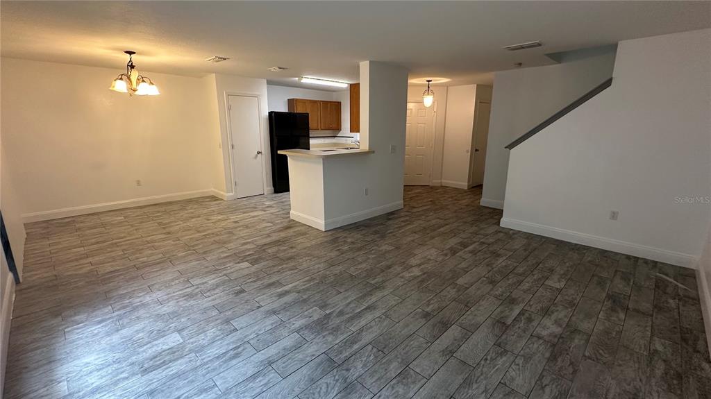 An open-concept living and dining area features wood-look tile flooring and a kitchen peninsula — 2437 HASSONITE STREET, KISSIMMEE, FL