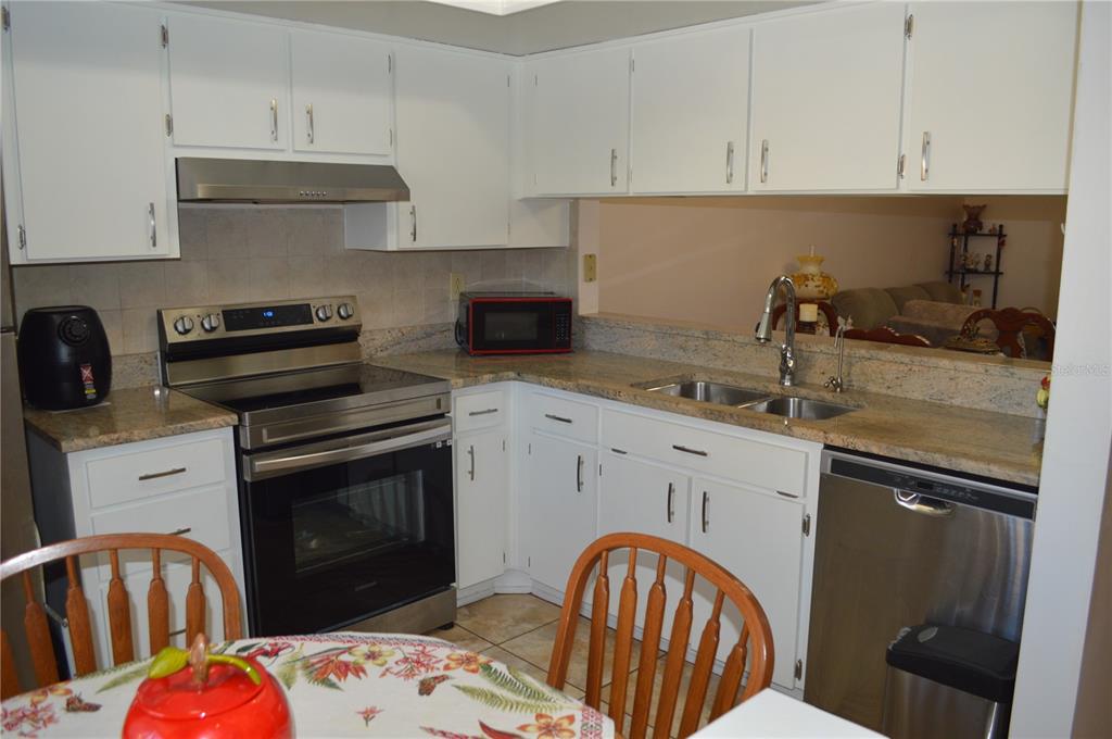 A kitchen features white cabinets, stainless steel appliances, and granite countertops — 38359 IRONWOOD PLACE UNIT 0, ZEPHYRHILLS, FL