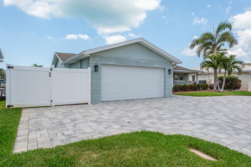 A light blue house with a stone facade, a white garage door, and a paved driveway — 11400 8TH STREET E, TREASURE ISLAND, FL