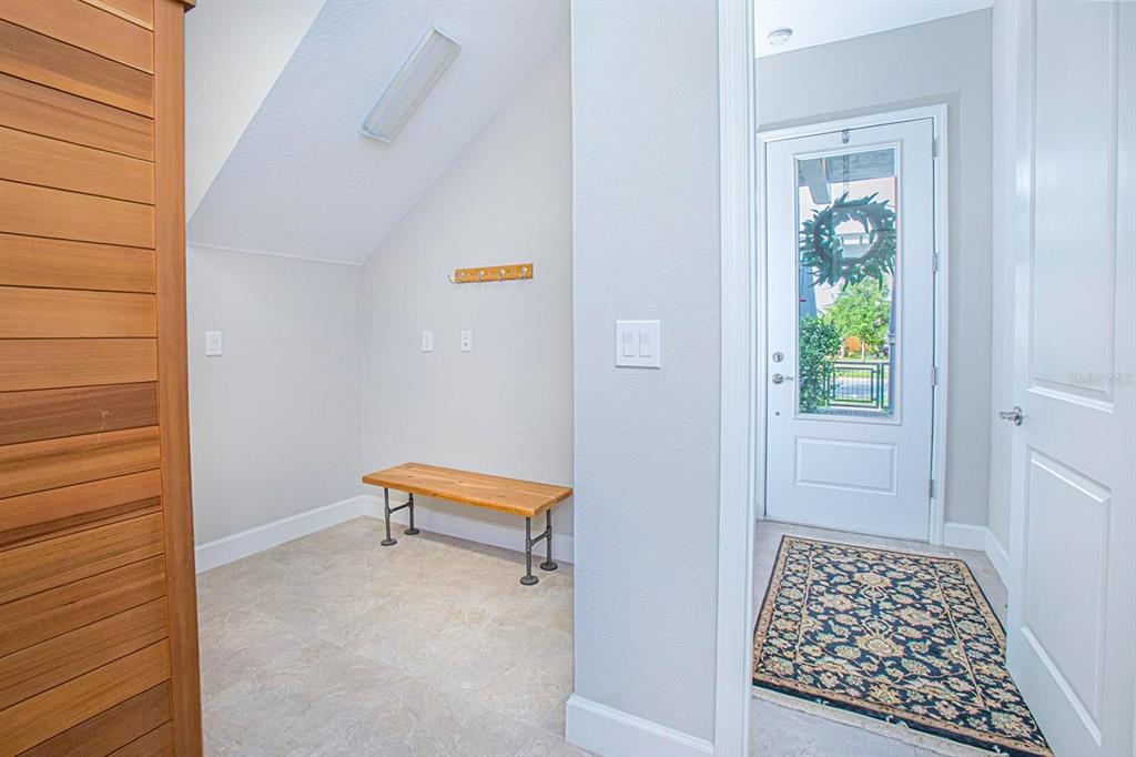 A mudroom with a wooden bench and coat rack sits beside an entryway with a door — 13413 GRANGER AVENUE, ORLANDO, FL