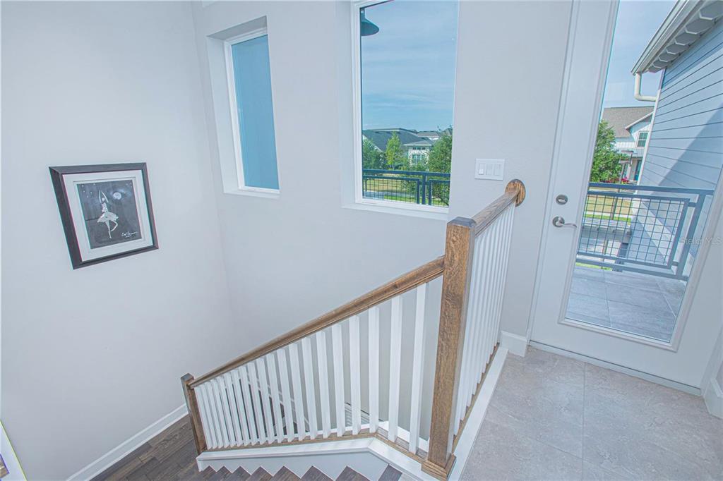 A staircase with white balusters and a wood handrail leads to a glass exterior door — 13413 GRANGER AVENUE, ORLANDO, FL