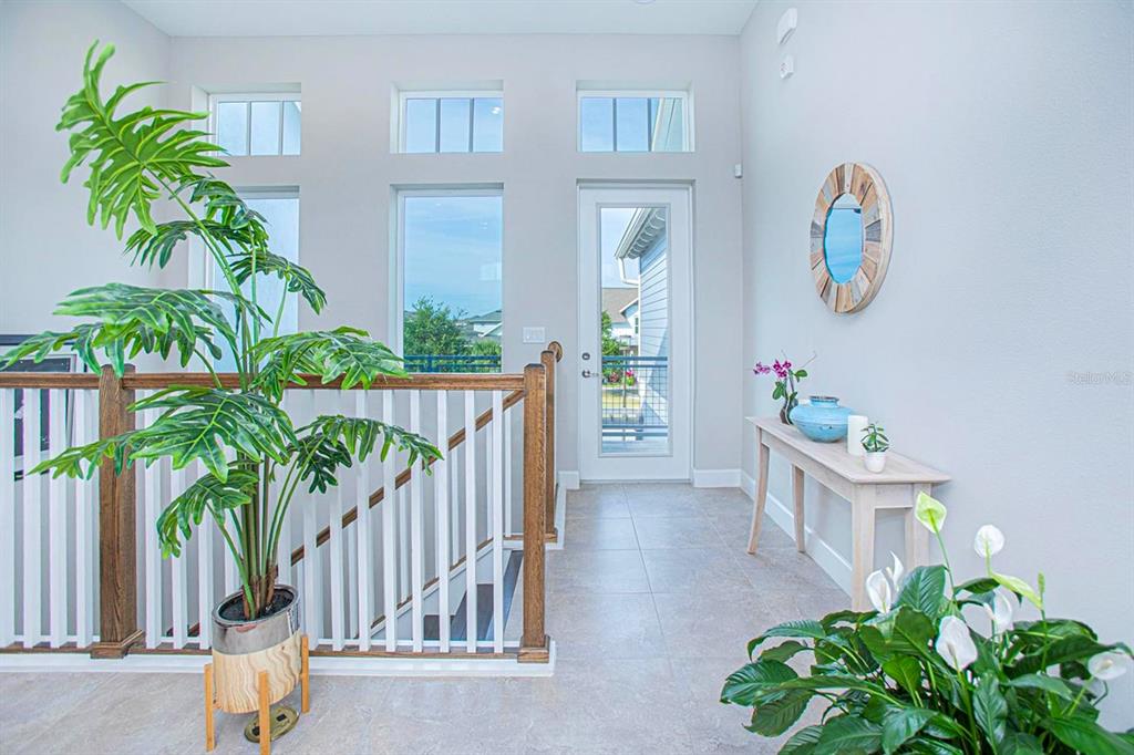 A bright landing area features a wooden staircase railing, tile flooring, and a glass door — 13413 GRANGER AVENUE, ORLANDO, FL