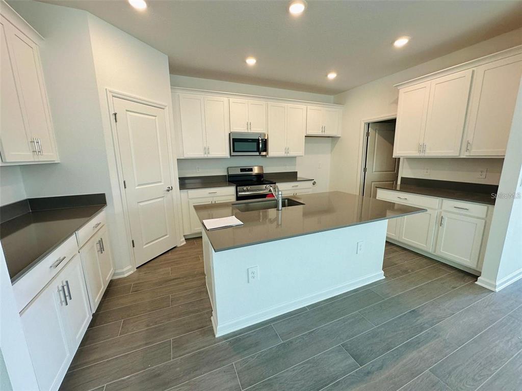 A kitchen features white cabinets, a central island with a sink, and dark countertops — 2665 ARMSTRONG AVENUE, CLERMONT, FL