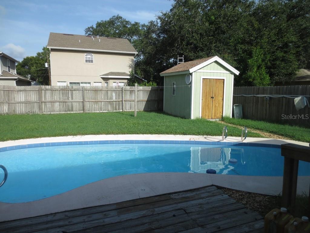 A backyard features a swimming pool, a wooden deck, a storage shed, and a wooden fence — 6713 S SHERIDAN ROAD, TAMPA, FL