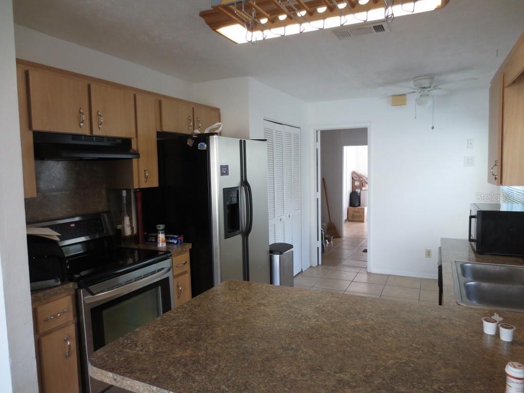 A kitchen features wood cabinets, stainless steel appliances, and a large island with laminate countertops — 6713 S SHERIDAN ROAD, TAMPA, FL