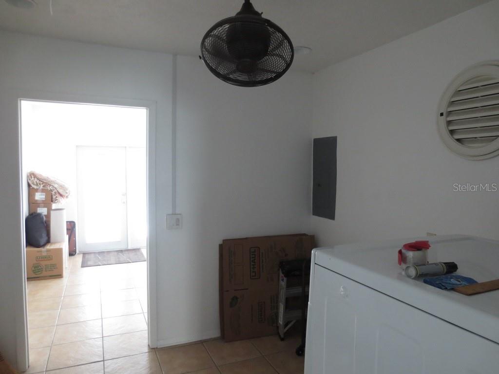 A laundry room features a ceiling fan, a breaker panel, and a doorway leading outside — 6713 S SHERIDAN ROAD, TAMPA, FL