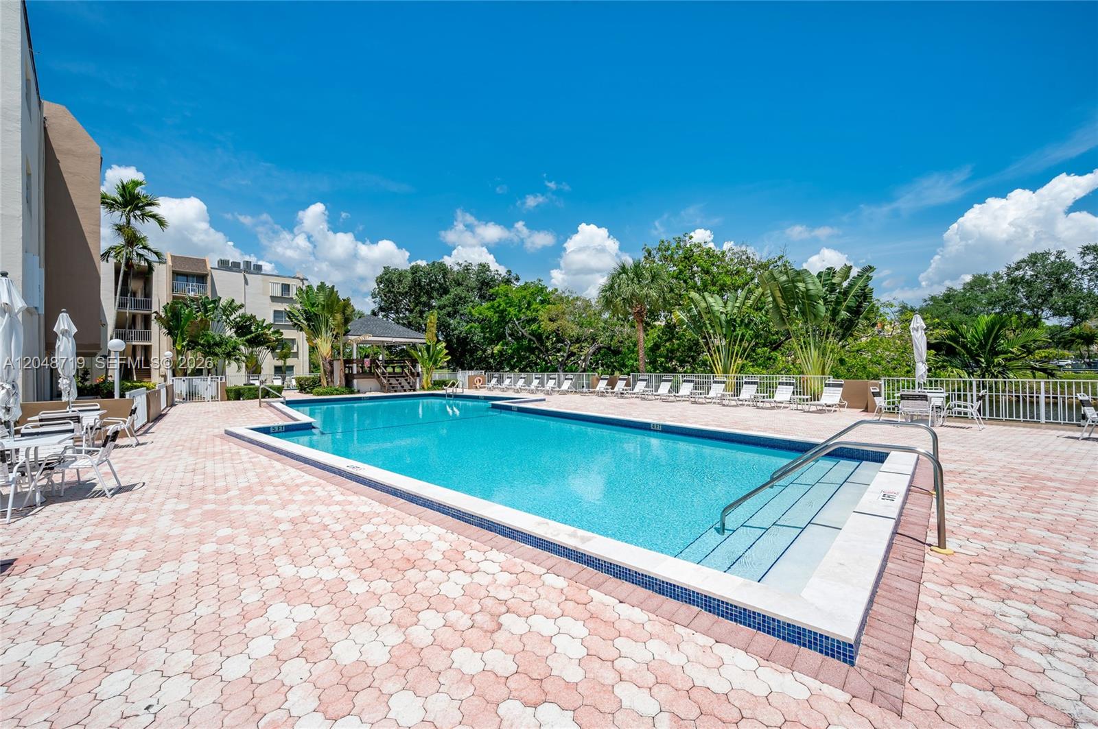 A kitchen features white cabinets, stainless steel appliances, light countertops, and tile flooring — 7705 SW 86th St # 114, Miami FL 33143, MIAMI, FL