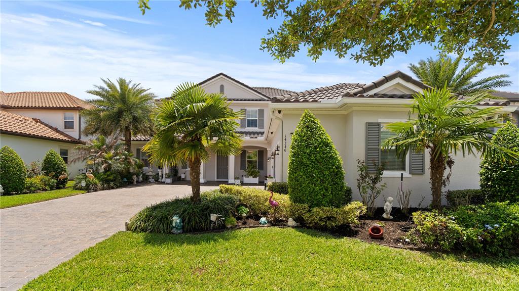 A two-story house with a paved driveway, palm trees, and manicured landscaping — 14240 COLONIAL POINTE DRIVE, WINTER GARDEN, FL