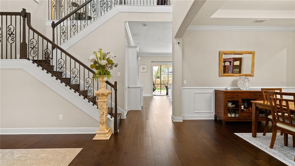 A foyer features a dark wood staircase with decorative railings, hardwood floors, and a dining area — 14240 COLONIAL POINTE DRIVE, WINTER GARDEN, FL