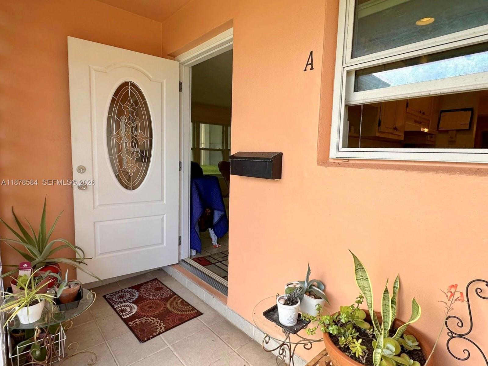 The exterior entrance of a home features an open door, a mailbox, and potted plants — 285 N High Point Blvd # A, Boynton Beach FL 33435, BOYNTON BEACH, FL