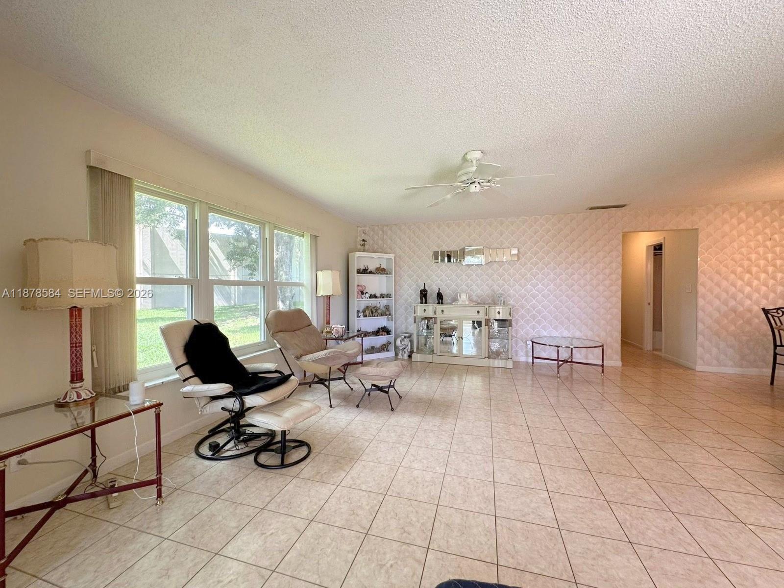 A living room features tiled floors, a patterned accent wall, and large windows — 285 N High Point Blvd # A, Boynton Beach FL 33435, BOYNTON BEACH, FL