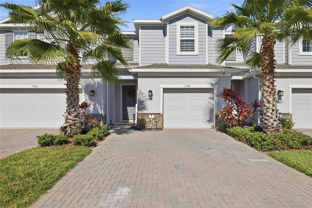 A two-story townhouse exterior features a paved driveway, a garage, and two palm trees — 1788 HOLDEN RIDGE LANE, MINNEOLA, FL