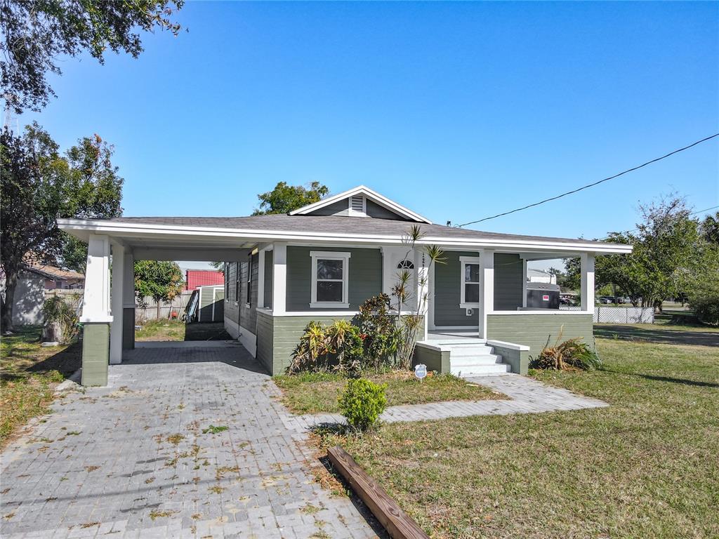 A single-story house with a green exterior, a front porch, and a paved carport — 1223 SYCAMORE STREET, LAKELAND, FL