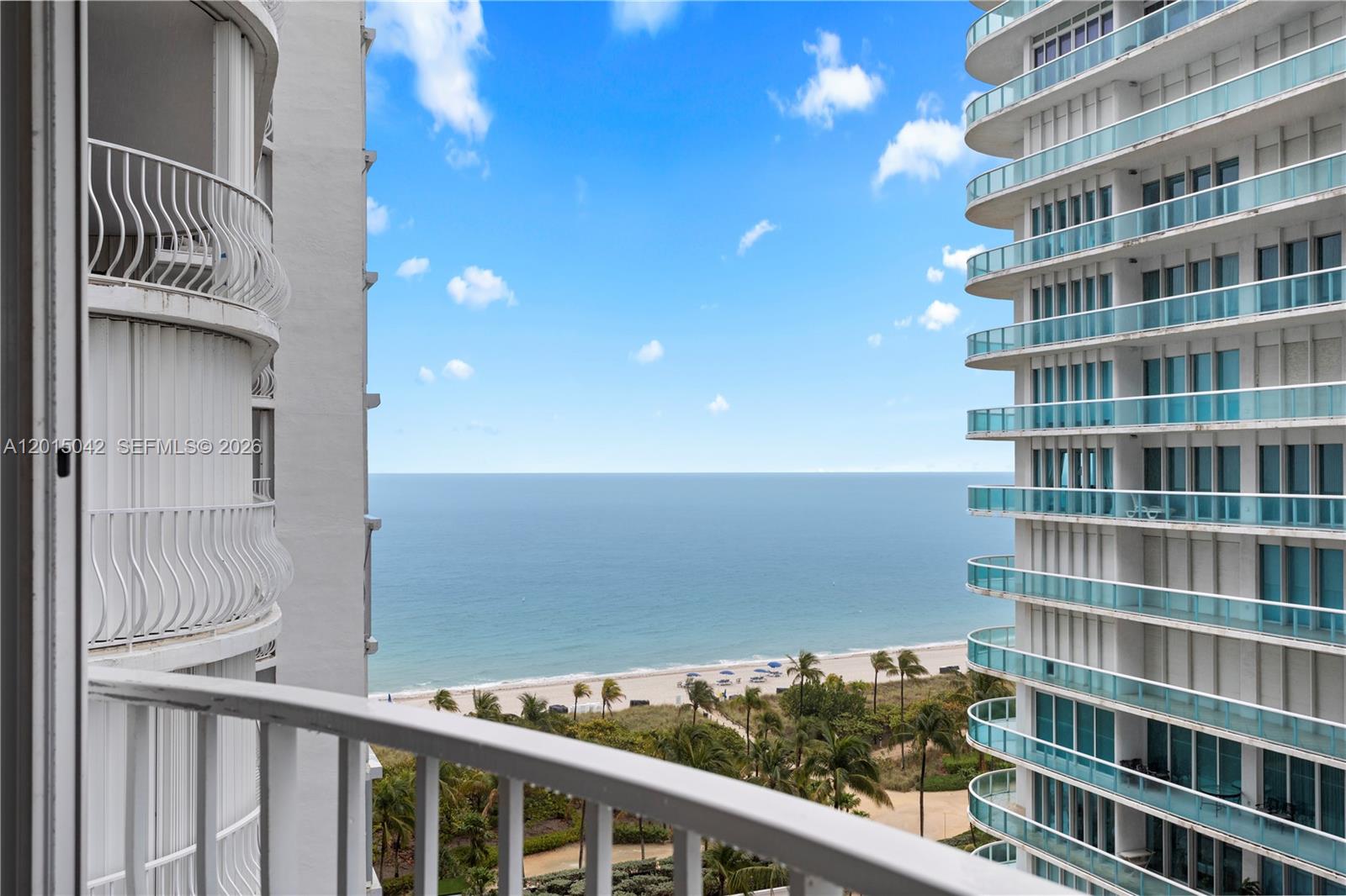 A balcony view overlooks a sandy beach and ocean between two high-rise apartment buildings — 10155 Collins Ave # 1105, Bal Harbour FL 33154, BAL HARBOUR, FL