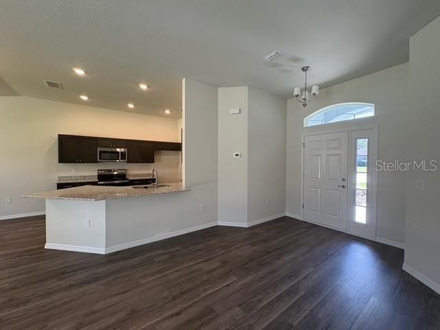An open-concept kitchen with dark cabinets and a breakfast bar overlooks a living area — 165 MARION OAKS PASS, OCALA, FL