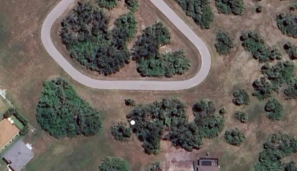 This aerial view shows a vacant, partially wooded residential lot situated along a curved road — 118 APRIL ROAD, ROTONDA WEST, FL