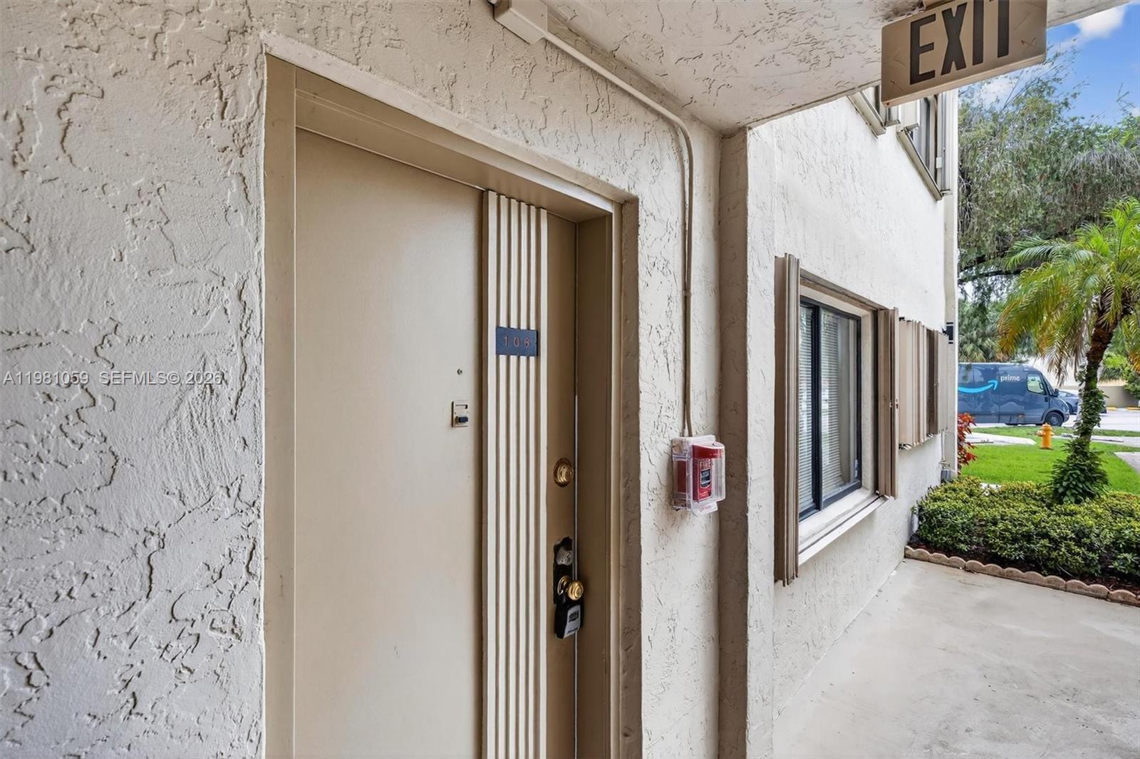 A beige apartment door labeled 106 is located on an exterior walkway with a fire alarm — 8065 SW 107th Ave # 106, Miami FL 33173, MIAMI, FL