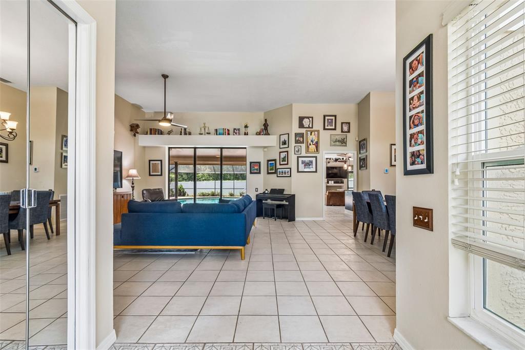 A view from a hallway into an open-concept living room with tile flooring and furniture — 2937 HILLCREEK CIRCLE S, CLEARWATER, FL