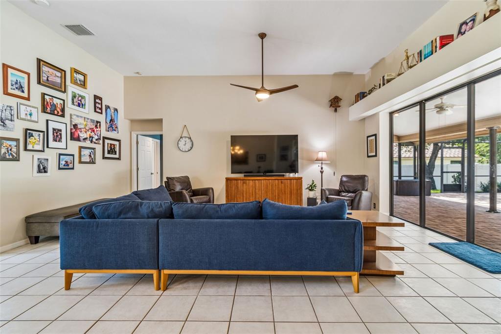 A living room features a blue sectional sofa, a television on a console, and tile flooring — 2937 HILLCREEK CIRCLE S, CLEARWATER, FL
