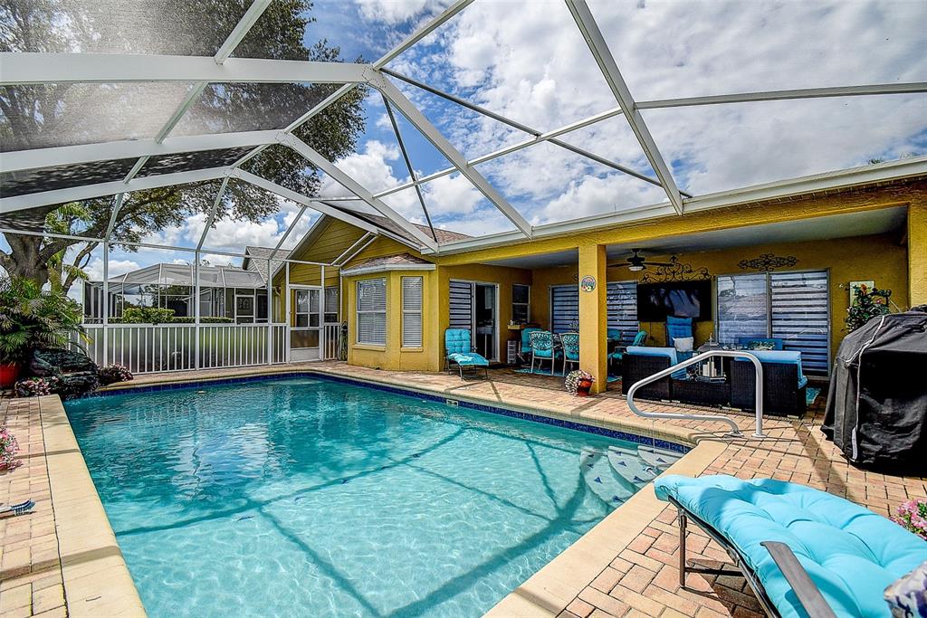A screened-in swimming pool with a patio and outdoor seating area next to a house — 18624 GRAND CLUB DRIVE, HUDSON, FL