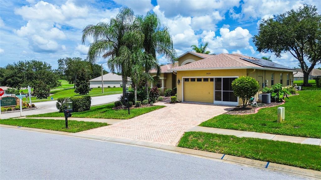 A single-story house with a tan exterior, a paved driveway, and a two-car garage — 18624 GRAND CLUB DRIVE, HUDSON, FL