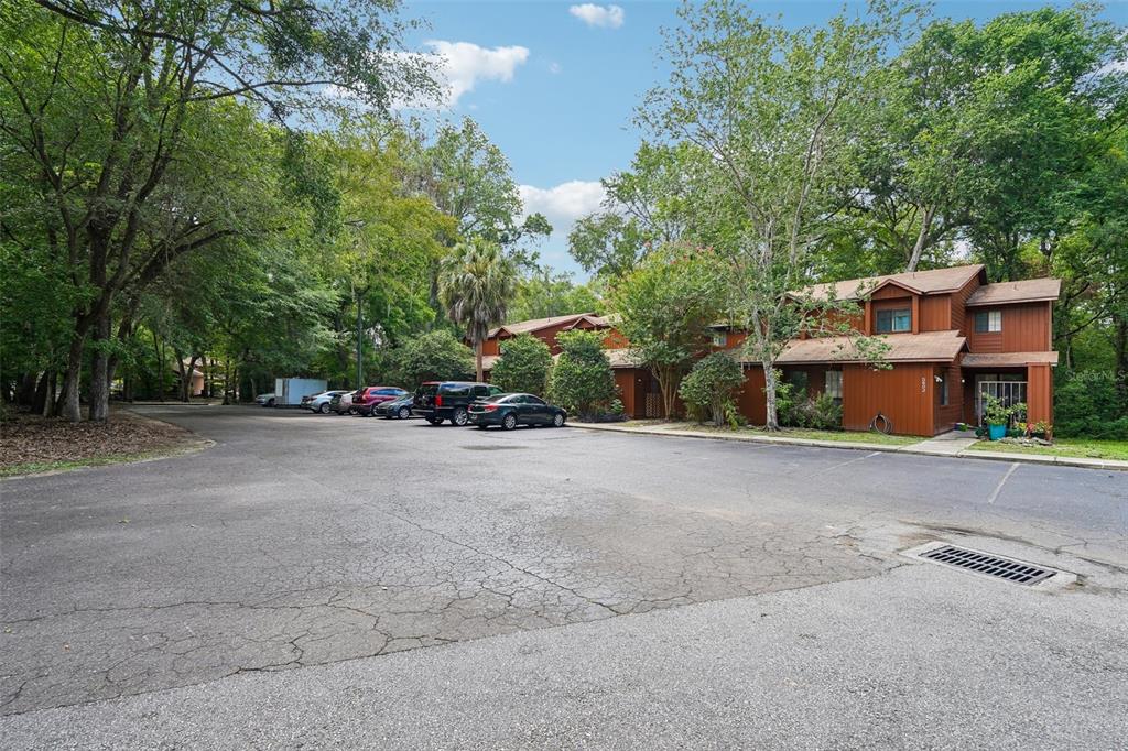 A multi-unit brown wooden building sits behind a paved parking lot surrounded by trees — 5606 SW 8TH PLACE, GAINESVILLE, FL