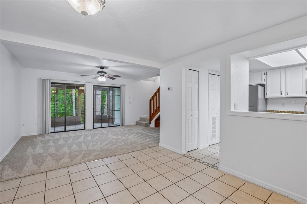 A living room with carpet, tile flooring, a ceiling fan, and sliding glass doors — 5606 SW 8TH PLACE, GAINESVILLE, FL