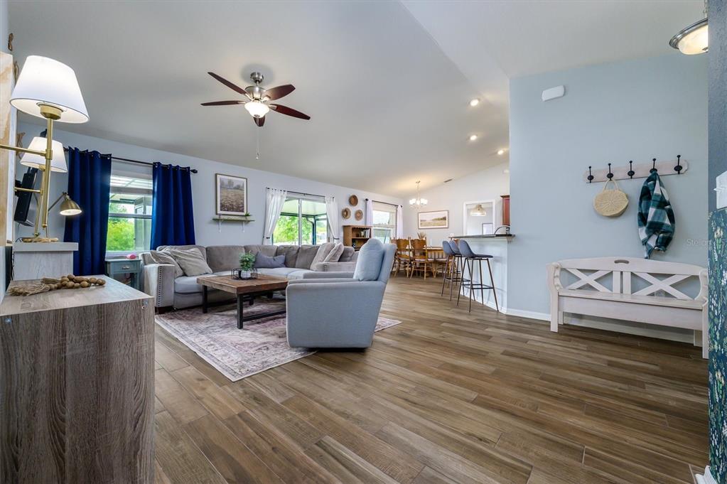 An open-concept living room and dining area feature wood-look tile flooring and blue walls — 708 TOWER GROVE DRIVE, PLANT CITY, FL