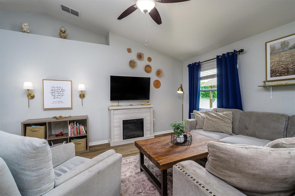 A living room features a fireplace, a television, a ceiling fan, and gray furniture — 708 TOWER GROVE DRIVE, PLANT CITY, FL
