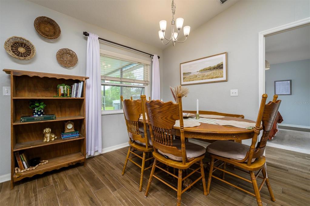A dining room features a wooden table, matching chairs, a bookshelf, and a chandelier — 708 TOWER GROVE DRIVE, PLANT CITY, FL